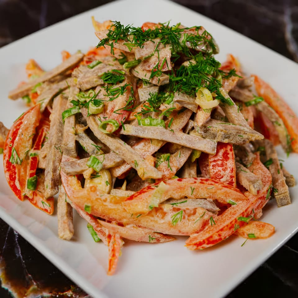 Halal salad with sliced meat, red bell peppers, and fresh dill on a white plate.